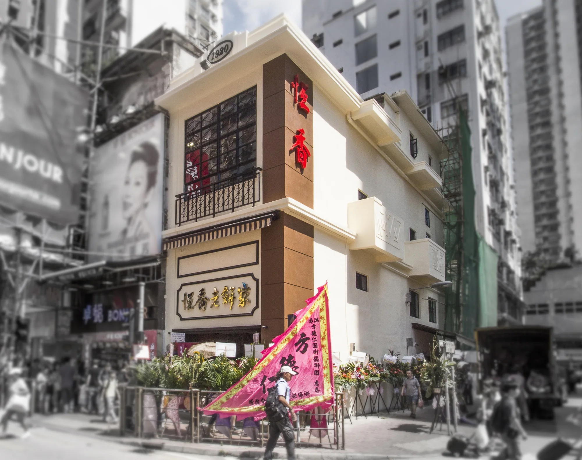 Historic Hong Kong bakery facade with cream stucco, brown trim, Chinese signage, ornate windows, and floral opening decorations.